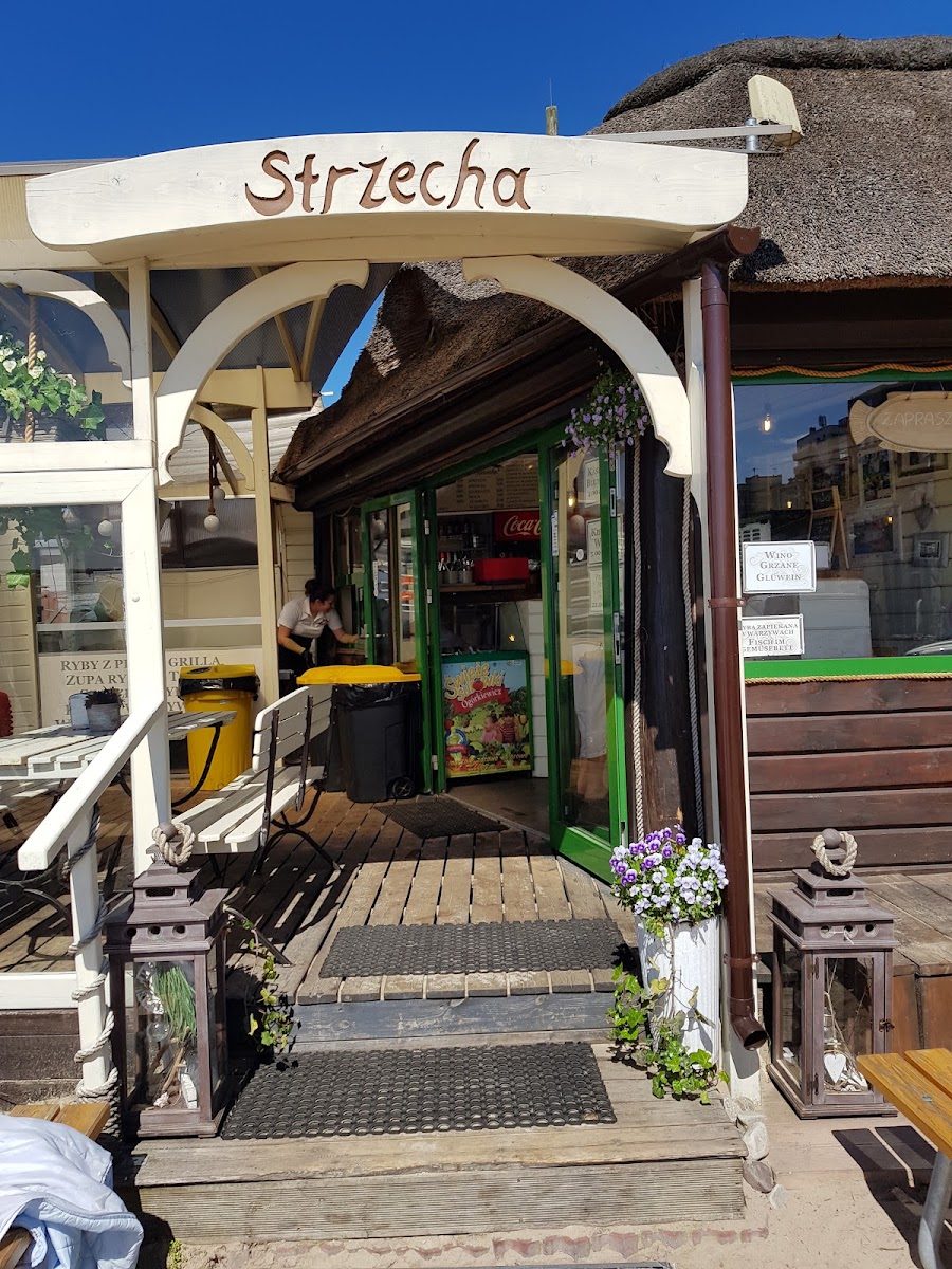 Wejście do Smażalni Strzecha z rzeźbionym szyldem i trzcinową strzechą